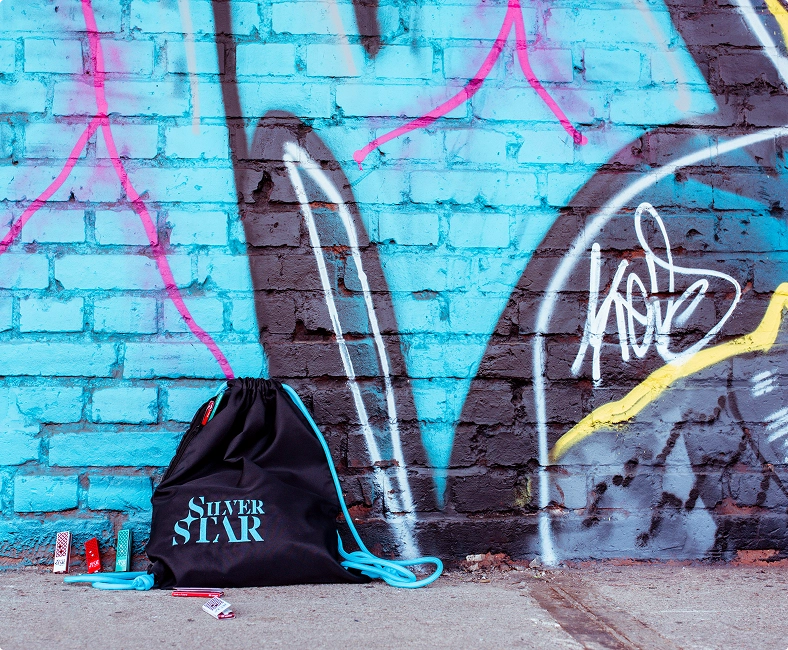 Czarny worek z napisem „Silver Star” leży na tle niebieskiej ściany z graffiti.