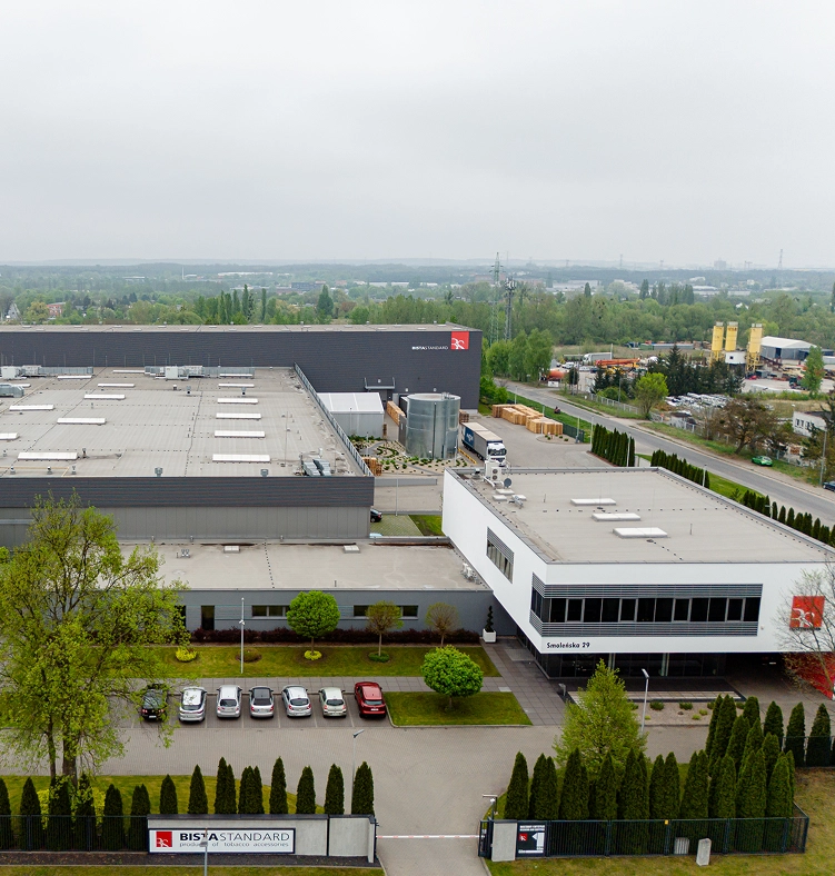 Nowy, duży budynek fabryczny z parkingiem i samochodami, widok z lotu ptaka.
